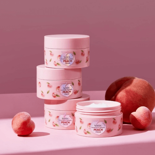 SOQU Pumping and Firming Peach Cream jars stacked with peach fruit on pink background.